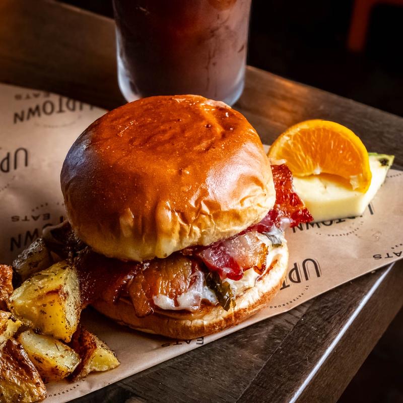 A brioche breakfast sandwich with a fried egg and roasted potatoes