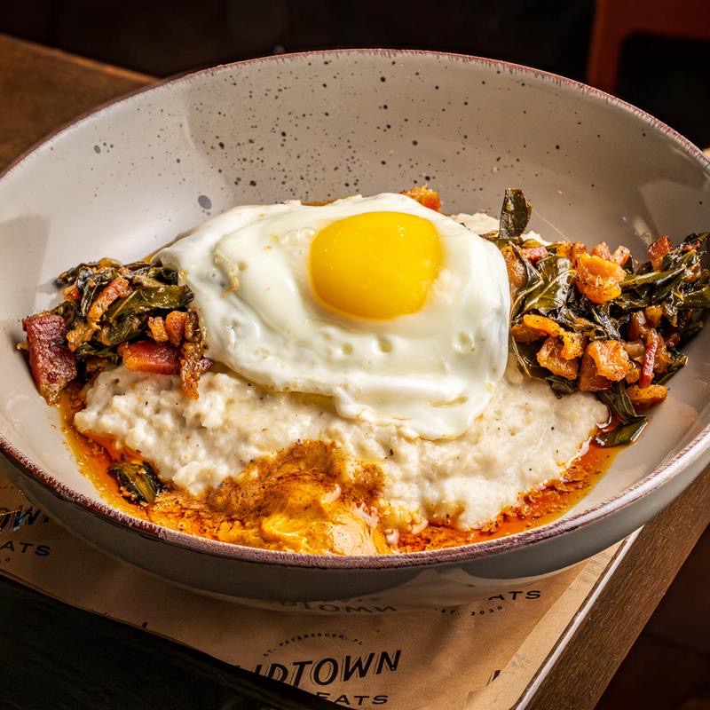A bowl of grits topped with greens and a fried egg